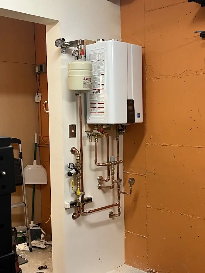 Plumbing technician inspecting water heater connections in Orchard Homes